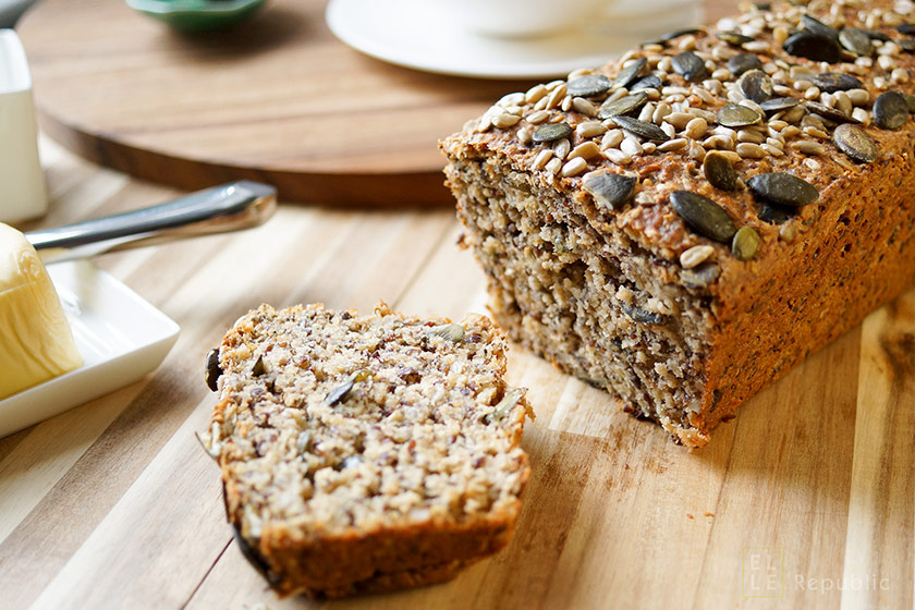 a sliced pumpkin bread generously topped with pumpkin seeds and nuts